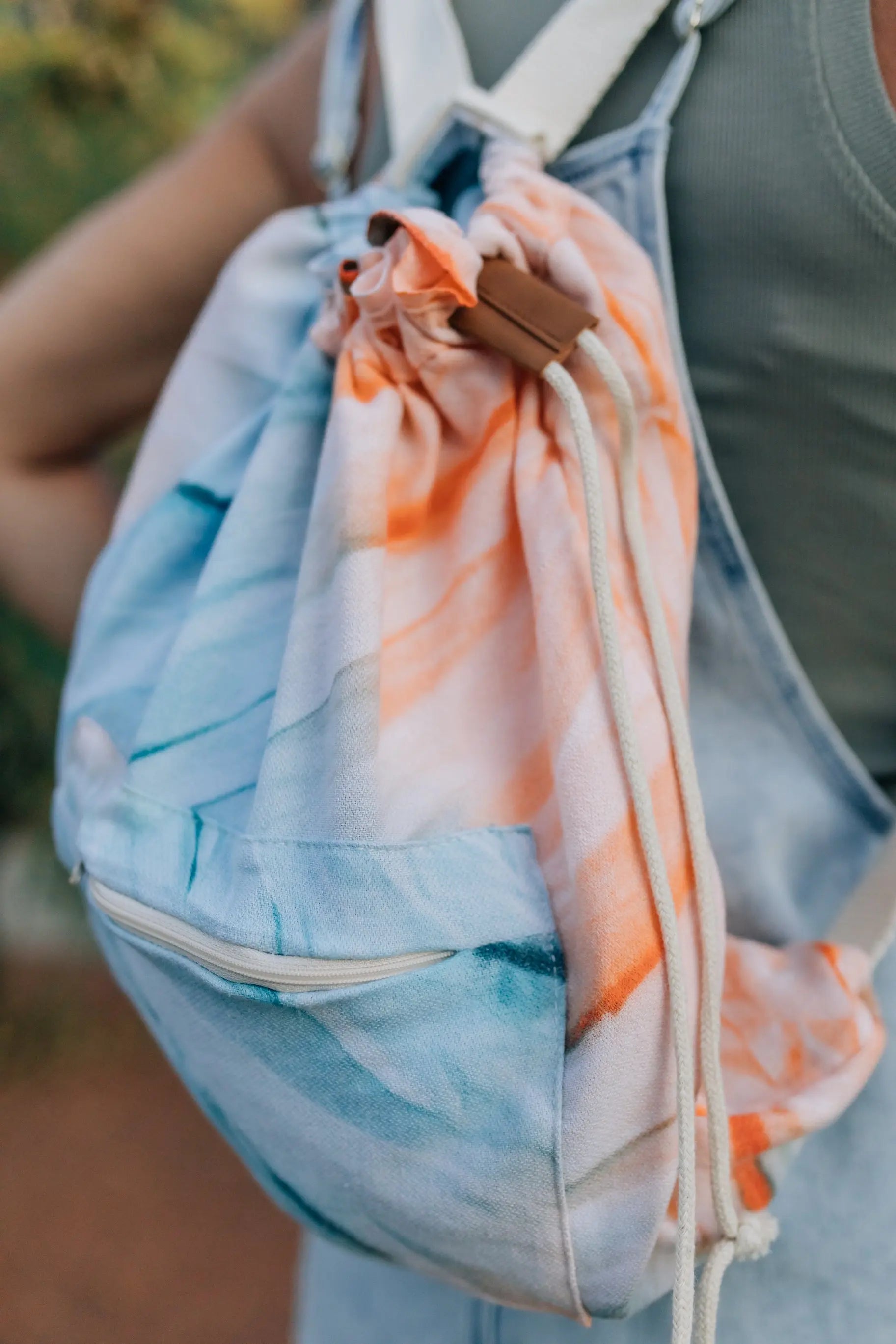 girl wearing towel backpack beach bag - blue and orange tie dye with drawstring and zipper  pocket light weight bag 