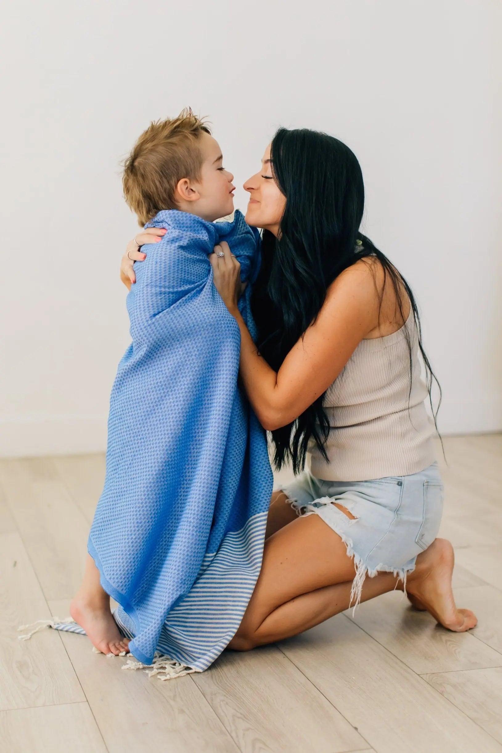 mother wrapping son in oversized bath beach and pool towel 