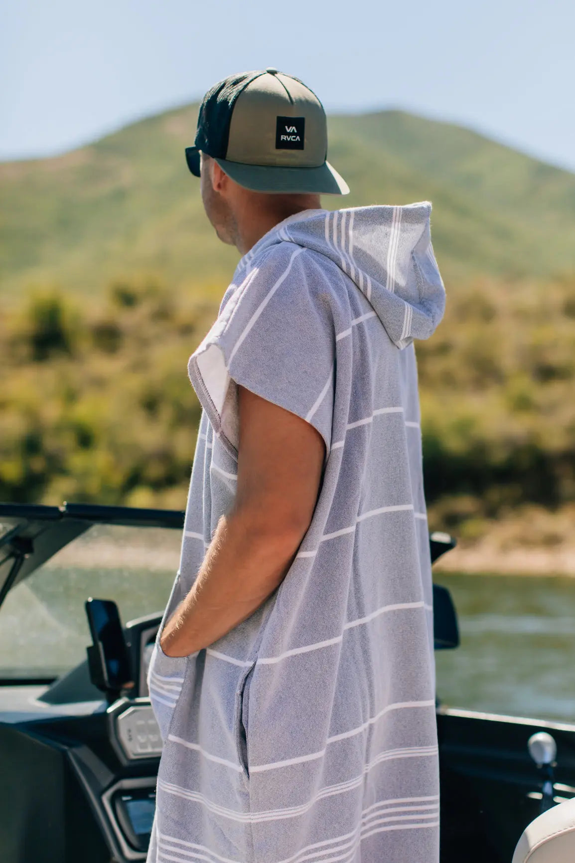 man driving boat wearing turkish surf poncho in gray stripe cotton 