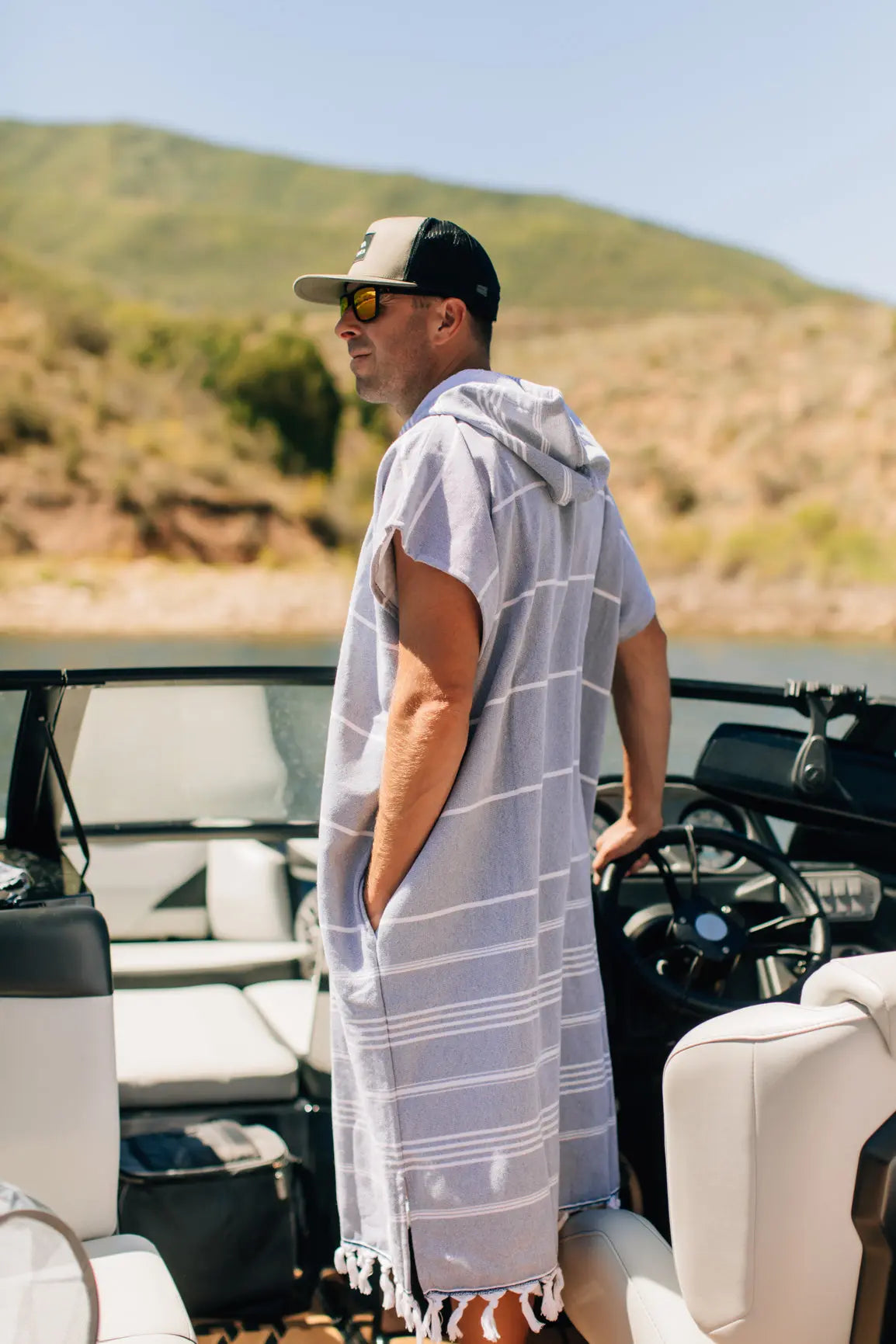 man in surf boat wearing blue hooded towel changing poncho 