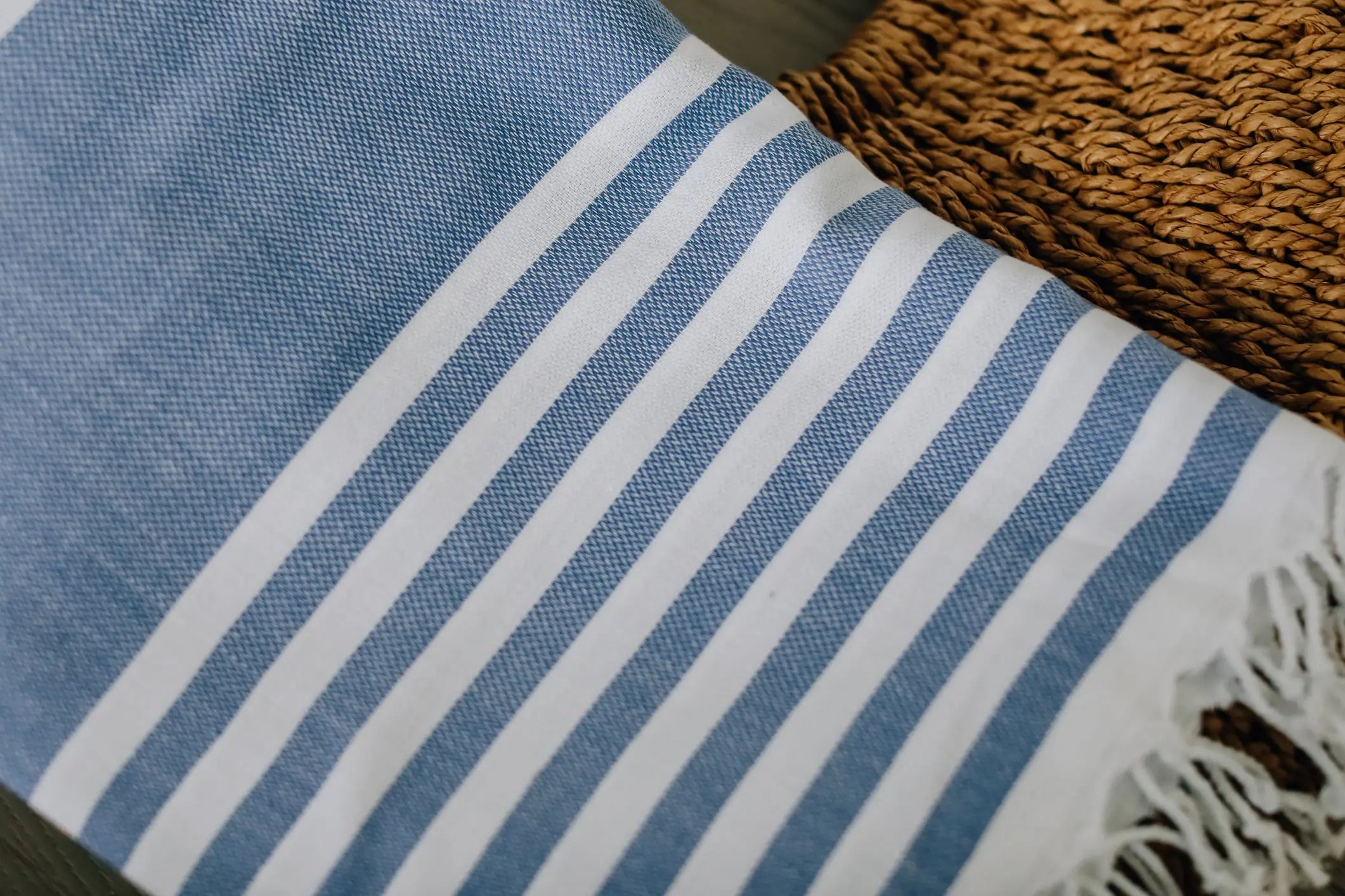 close up of cabana print turkish towel . blue and white stripe with  tassels 