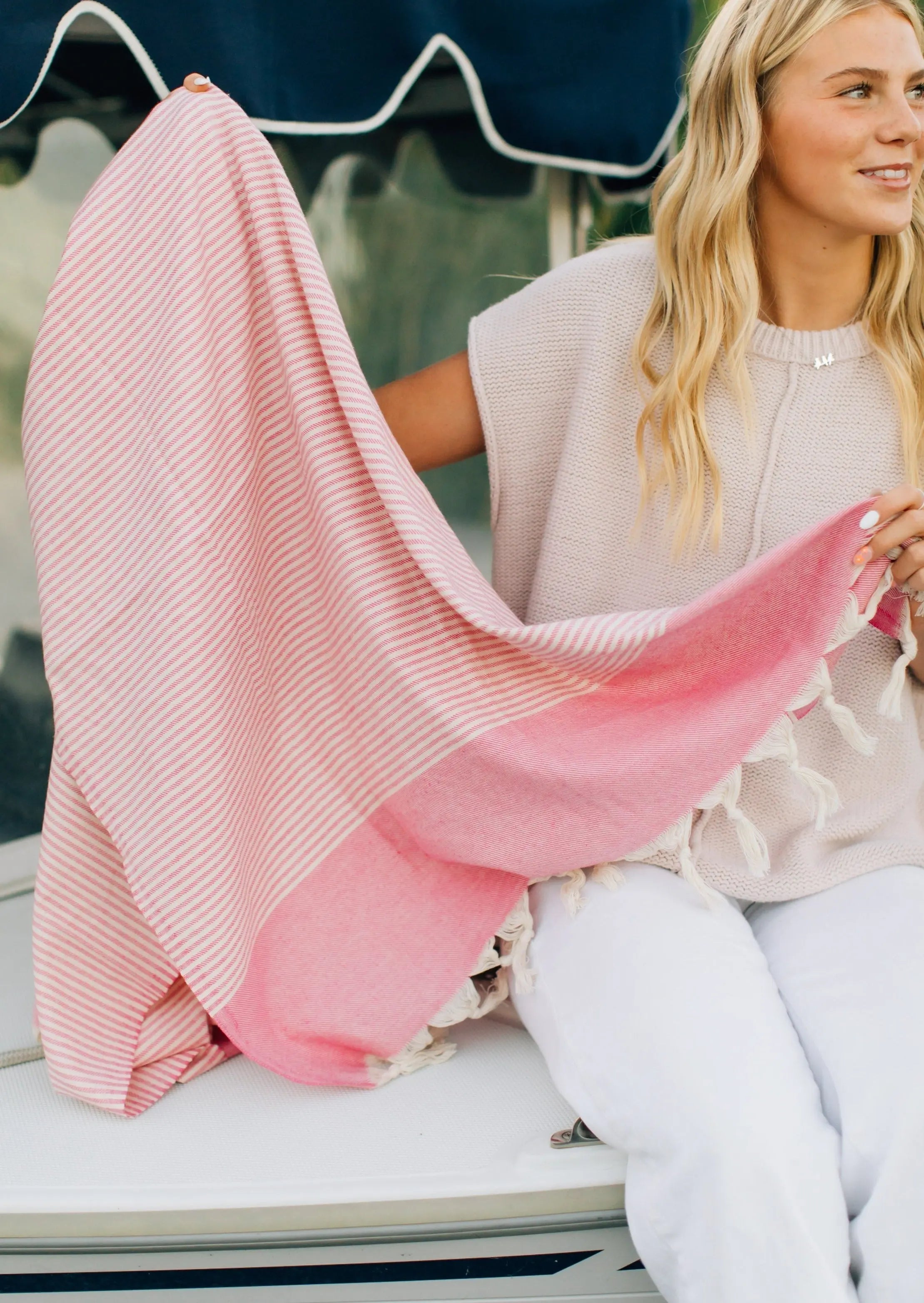 girl on boat holding pink turkish towel with stripes. traditional pattern. soft beach towel. 